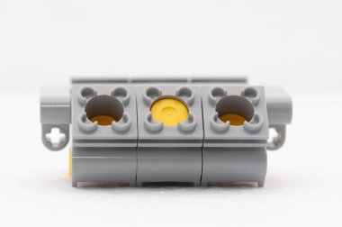 Sarı parçalı gri oyuncak bir motor. Beyaz bir yüzeyde duruyor. Lego. Polonya, Varşova 06.12.2024