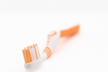 Turuncu tüyleri ve beyaz tüyleri olan bir diş fırçası. Diş fırçası beyaz arka planda duruyor.