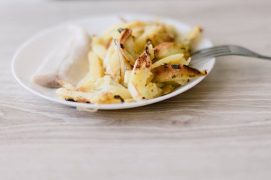 Üzerinde çatal olan bir tabak yemek. Tabakta bir parça et ve patates var.