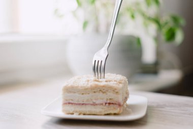 Bir parça pasta yemek için bir çatal kullanılıyor. Pasta tabakta.