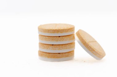 Dört hap üst üste istiflenmiş. Hepsi aynı renk ve boyutta. Haplar beyaz ve sarı.