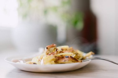 Üzerinde çatal olan bir tabak yemek. Yemek patatestir ve beyaz tabakta.