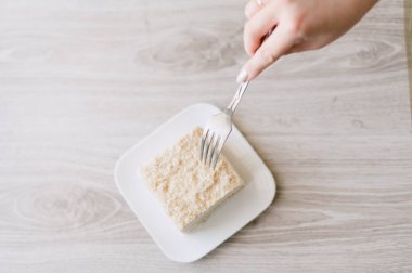 Bir parça pasta yemek için bir çatal kullanılıyor. Çatal beyaz bir tabakta.