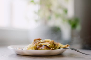 Üzerinde çatal olan bir tabak yemek. Yemek patatestir ve beyaz tabakta.