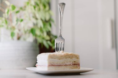 Bir parça pasta yemek için bir çatal kullanılıyor. Pasta tabakta.