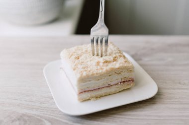 Bir parça pasta yemek için bir çatal kullanılıyor. Pasta tabakta.