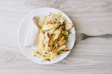 Üzerinde çatal olan bir tabak yemek. Tabakta bir parça et ve patates var.