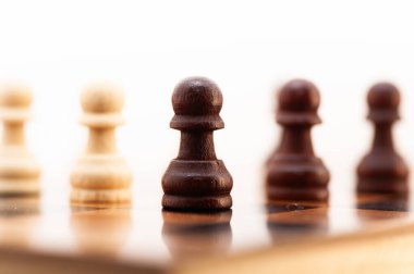 Siyah beyaz bir satranç taşı diğer taşlarla birlikte tahtada duruyor. O bir piyon, tahtanın en küçük ve en az güçlü parçası. Piyon tahtanın ortasına yerleştirildi.