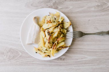 Üzerinde çatal olan bir tabak yemek. Tabakta bir parça et ve patates var.