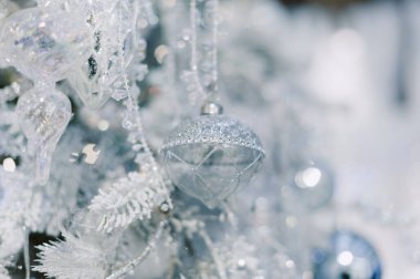 Üzerinde gümüş top olan bir ağaç. Top karla çevrili. Ağaçta başka toplar da var.