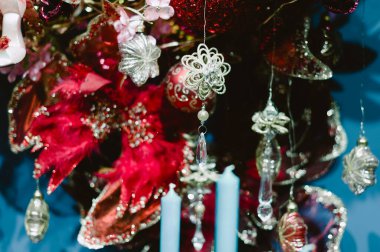 Bir sürü süs ve mumla süslenmiş güzel bir Noel ağacı. Mumlar mavi ve ağaçtan sarkmış sıcak ve şenlikli bir atmosfer yaratıyorlar. Ağaç kırmızıyla süslenmiş.