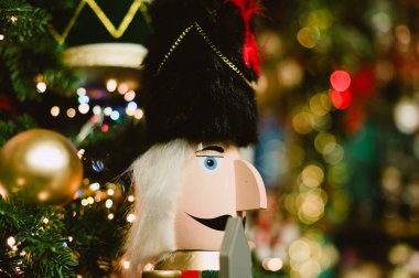 Bir fındıkkıran Noel ağacında oturuyor. Fındıkkıran siyah bir şapka takıyor ve mavi bir yüzü var.