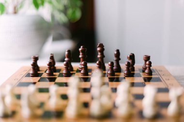 Üzerinde taşlar olan bir satranç tahtası. Tahta siyah beyaz. Parçalar bir oyun oynamaya hazır bir şekilde düzenlenir.