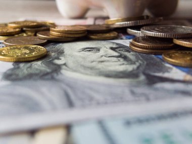 Bir yığın bozuk para ve bir dolarlık banknot. Bozuk paraların boyutları ve renkleri farklı.