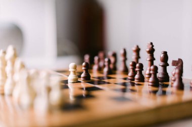 Üzerinde birkaç parça olan tahta bir satranç tahtası. Tahta bir satranç oyunu için kurulmuş.