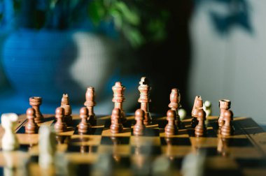 Üzerinde taşlar olan tahta bir satranç tahtası. Tahta masanın üstünde ve arka planda bir Noel ağacı var.