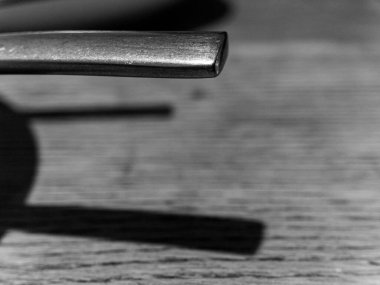 Ahşap bir yüzeyde iki metal nesne var. Nesnelerden biri eğilmiş. Diğer nesne eğri değil