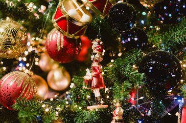 Kırmızı ve altın varili olan bir Noel ağacı ve yeşil ve altın bir asker. Ağaç ışıklarla aydınlanıyor.