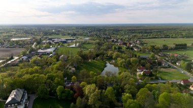 Evleri ve göleti olan küçük bir kasaba manzarası. Gökyüzü bulutlu ve kasaba bir tarlanın ortasında gibi görünüyor. Hava fotoğrafçılığı