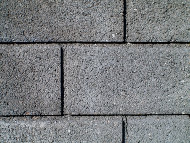 Ortasında siyah çizgi olan gri tuğla bir duvar. Tuğlalar üst üste dizilmiş.