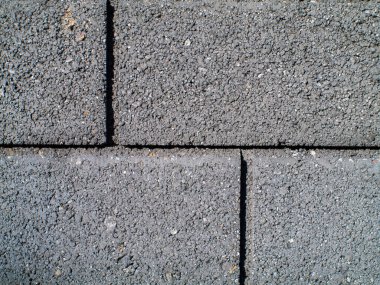 Üzerinde gri tuğla olan gri bir duvar. Tuğla gri ve üzerinde siyah bir çizgi var.