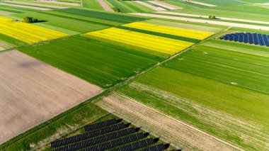 Ortasında birkaç siyah kare olan bir ekin tarlası. Alan yeşil ve sarı. Gökyüzü manzarası.