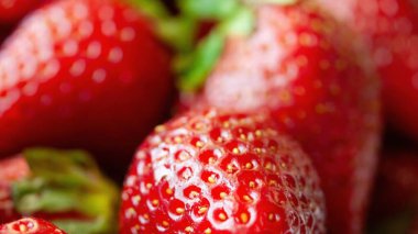 Bir sürü kırmızı çilek yakın çekim. Çilekler taze ve olgun, parlak kırmızı bir rengi ve hafif bulanık bir görüntüsü var. Zenginlik ve tazelik kavramı