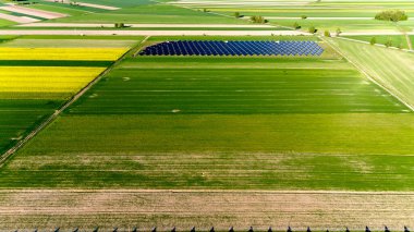 Ortasında güneş paneli olan bir ekin tarlası. Güneş paneli bir çitle çevrili. Havadan