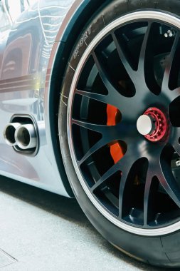 Üzerinde spor harfleri olan siyah lastik. Lastik bir arabanın üzerinde. Araba bir otoparkta park halinde. Telefon duvar kâğıdı. Dikey arkaplan.