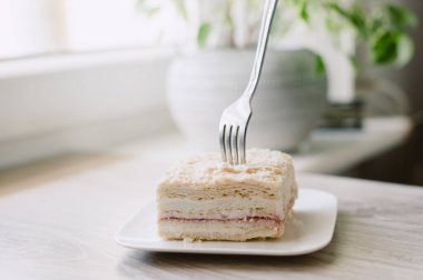 Bir parça pasta yemek için bir çatal kullanılıyor. Pasta tabakta.