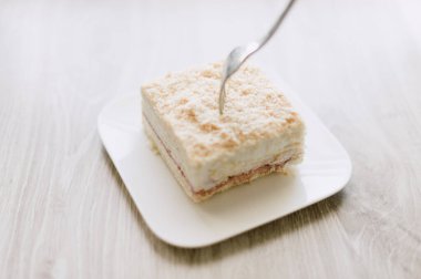 Bir çatal bir dilim kekle birlikte bir tabağın üzerindedir. Çatal gümüş.