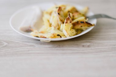 Üzerinde çatal olan bir tabak yemek. Tabakta bir parça et ve patates var.