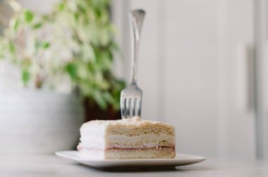 Bir parça pasta yemek için bir çatal kullanılıyor. Pasta tabakta.