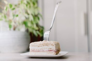 Bir parça pasta yemek için bir çatal kullanılıyor. Pasta tabakta.