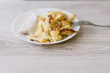 Üzerinde çatal olan bir tabak yemek. Tabakta bir parça et ve patates var.