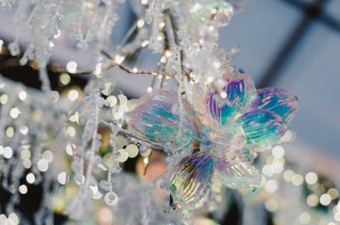 Üzerinde mavi ve beyaz bir çiçek olan bir ağaç. Çiçek camdan yapılmış ve ağaçtan sarkıyor.