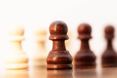 Siyah beyaz bir satranç taşı diğer taşlarla birlikte tahtada duruyor. O bir piyon, tahtanın en küçük ve en az güçlü parçası. Piyon tahtanın ortasına yerleştirildi.