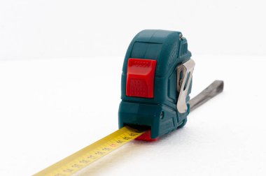 Üzerinde kırmızı beyaz bir düğme olan bir mezura. Şerit ölçü sarı ve mavi.