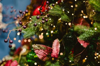 Yeşil ve kırmızı süslemeli bir Noel ağacı. Ağacın kırmızı kurdeleli yeşil bir süsü var.