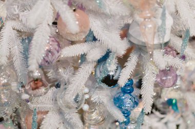 Bir sürü süslemesi olan beyaz bir Noel ağacı. Zil de dahil. Ağaçta başka süslemeler de var.