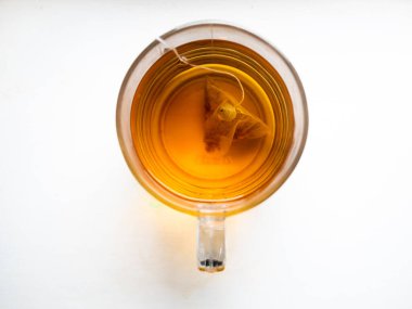 İçinde çay poşeti olan bir kupa çay. Çay poşeti fincanın ortasında yüzüyor. Çay açık kahverengiydi ve taze demlenmişti.