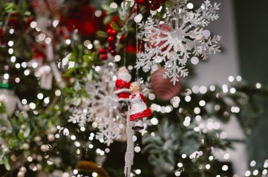 Üstünde kar tanesi süsü asılı bir Noel ağacı. Kar taneleri kırmızı ve beyaz bir dizaynla çevrilidir..