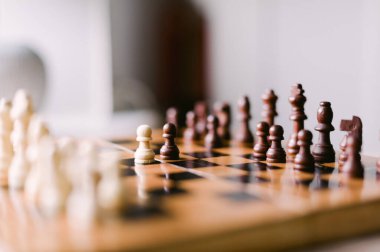 Üzerinde birkaç parça olan tahta bir satranç tahtası. Tahta bir satranç oyunu için kurulmuş.