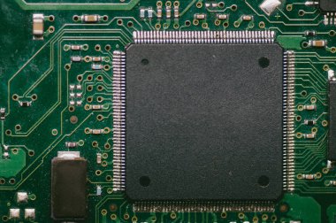 Yeşil devre kartında siyah bir çip. Çip siyah ve beyaz çizgileri var.