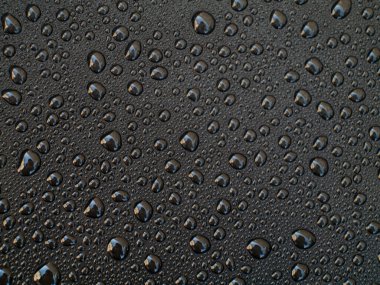 Bir sürü küçük su damlası olan siyah bir zemin. Damlalar her yere saçılmış.