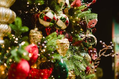 Üzerinde birçok süs bulunan bir Noel ağacı. Süsler yeşil, kırmızı ve beyazdır.