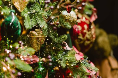 Kırmızı ve yeşil süslemeli bir Noel ağacı. Kırmızı süsler kalpler, yeşil olanlar da çanlar.