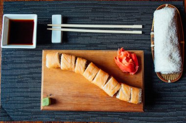 Çubuklu bir tabak suşi ve küçük bir kase sos. Suşi uzun şeritlere ayrılır ve ahşap bir tahtanın üzerinde servis edilir. Çubuklar masanın üzerine, suşinin yanına konur.