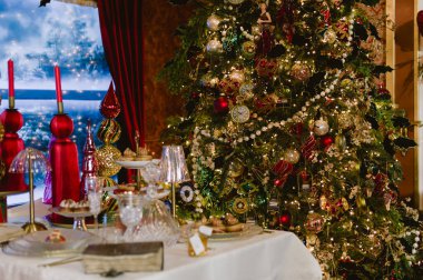 Arka planda Noel ağacı olan bir masa. Masada bir sürü mum var.