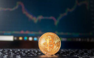 Üzerinde Bitcoin olan bir altın sikke klavyede. Klavye masanın üstünde.